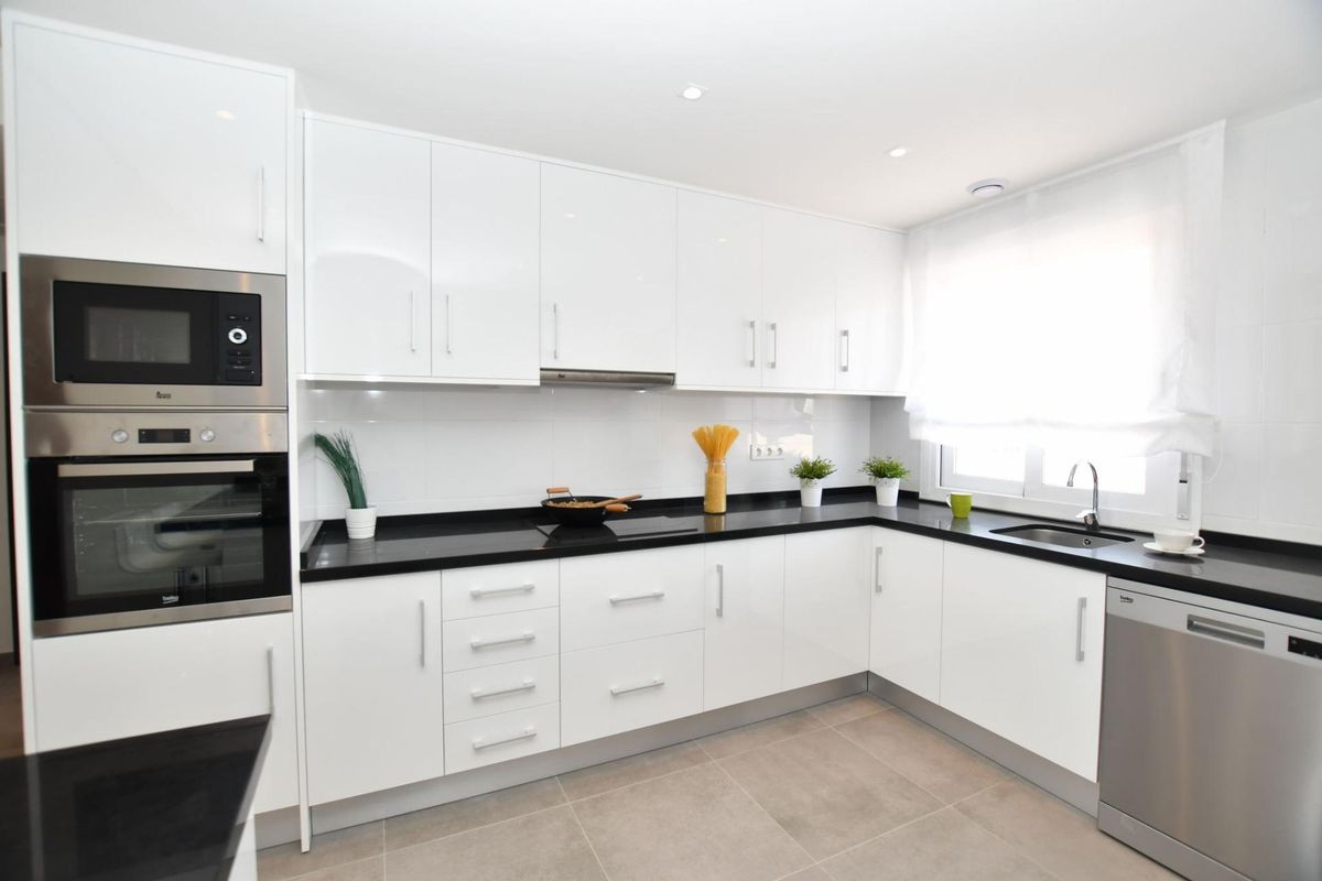 Efficiënte keukenruimte in een 2-slaapkamer bungalow, moderne apparaten benadrukt in San Miguel de Salinas, Spanje.