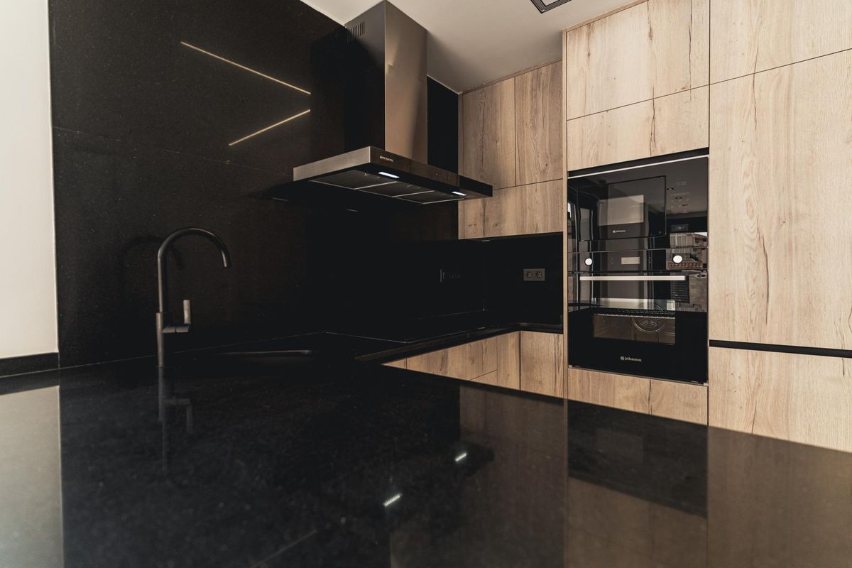 Close-up van een stijlvolle keukenblad met zwart graniet en lichte houten kasten in Orihuela Costa, Spanje.