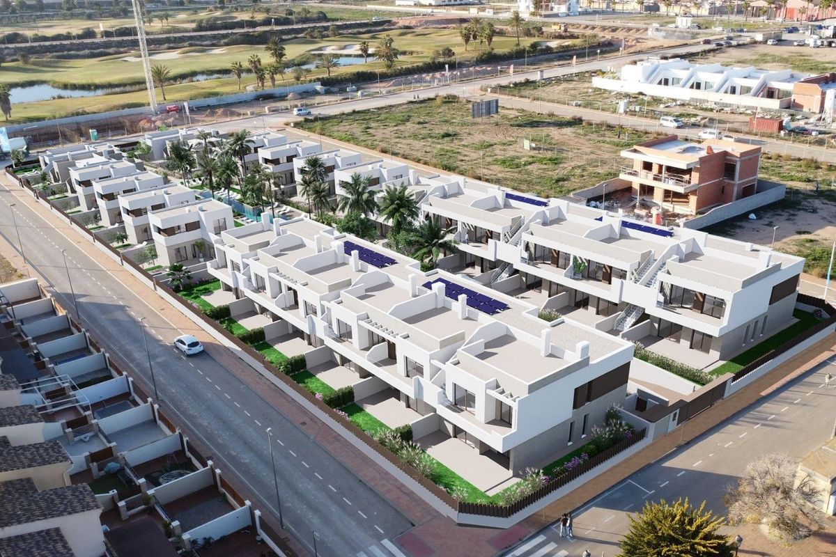 Straatbeeld van moderne bungalows met strakke lijnen en groene tuinen in Los Alcazares, Spanje.