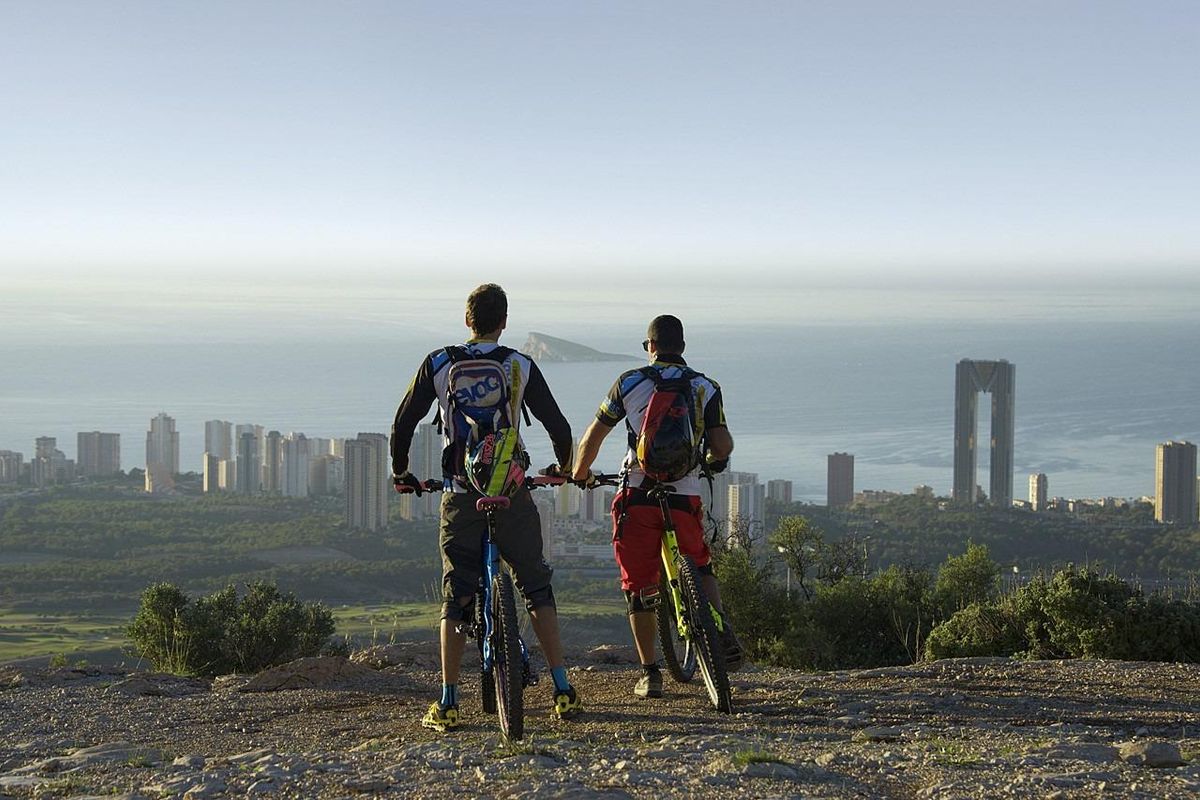 Twee fietsers genieten van het uitzicht op de bergen boven Benidorm en de Middellandse Zee.