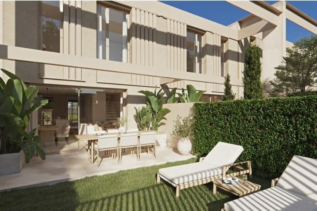 Achtertuin van het townhouse in Godella, met eetruimte en ligstoelen omringd door groen.