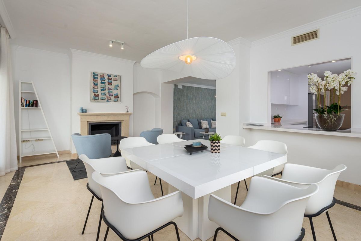 Heldere eetruimte met een grote tafel en moderne stoelen in een villa in Estepona, met een gezellige open haard.