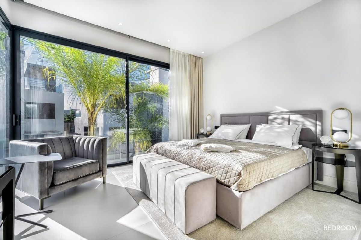 Comfortabele slaapkamer met een groot bed en ramen die natuurlijk licht binnenlaten, gelegen in villa in Marbella.