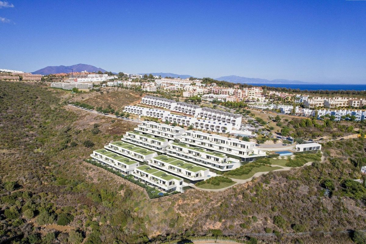 Aerial view of a new development of modern townhouses in Manilva, Costa del Sol, set on a hillside overlooking the coast.