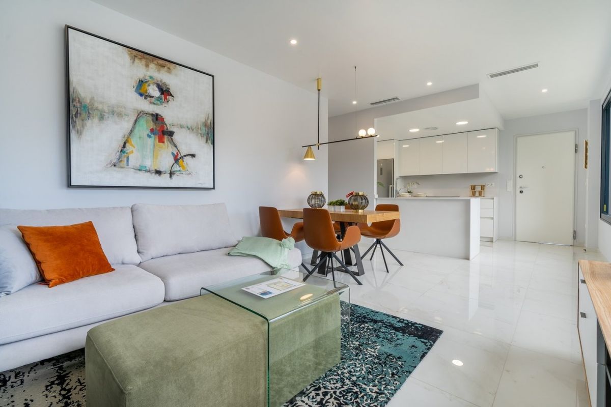 Heldere woonkamer met een comfortabele bank, toegang tot de keuken en stijlvolle inrichting in een 2-slaapkamer appartement in Benidorm.