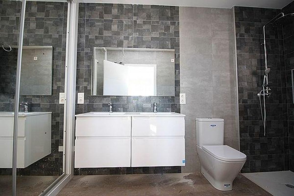 Moderne badkamer met grote tegels, dubbele wastafel en douche, ontworpen voor comfort aan de Costa Blanca Zuid.