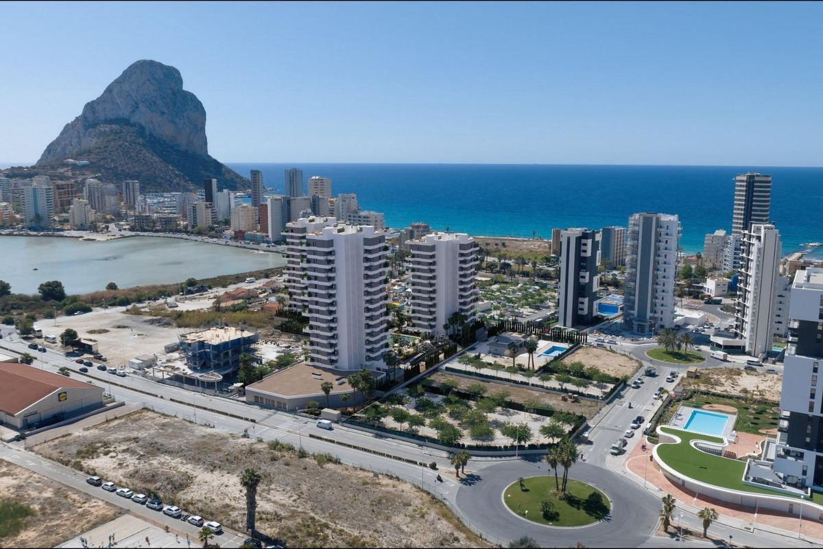 Aerial view of Calpe showing coastal landscape, high-rise buildings, and the iconic Peñón de Ifach in the background.