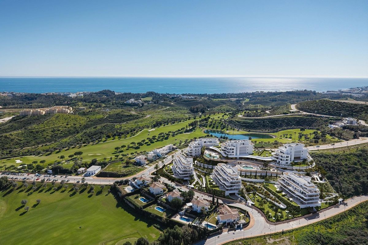 Luchtfoto van een luxe appartement complex in Mijas, omringd door groene heuvels en kustlijn.