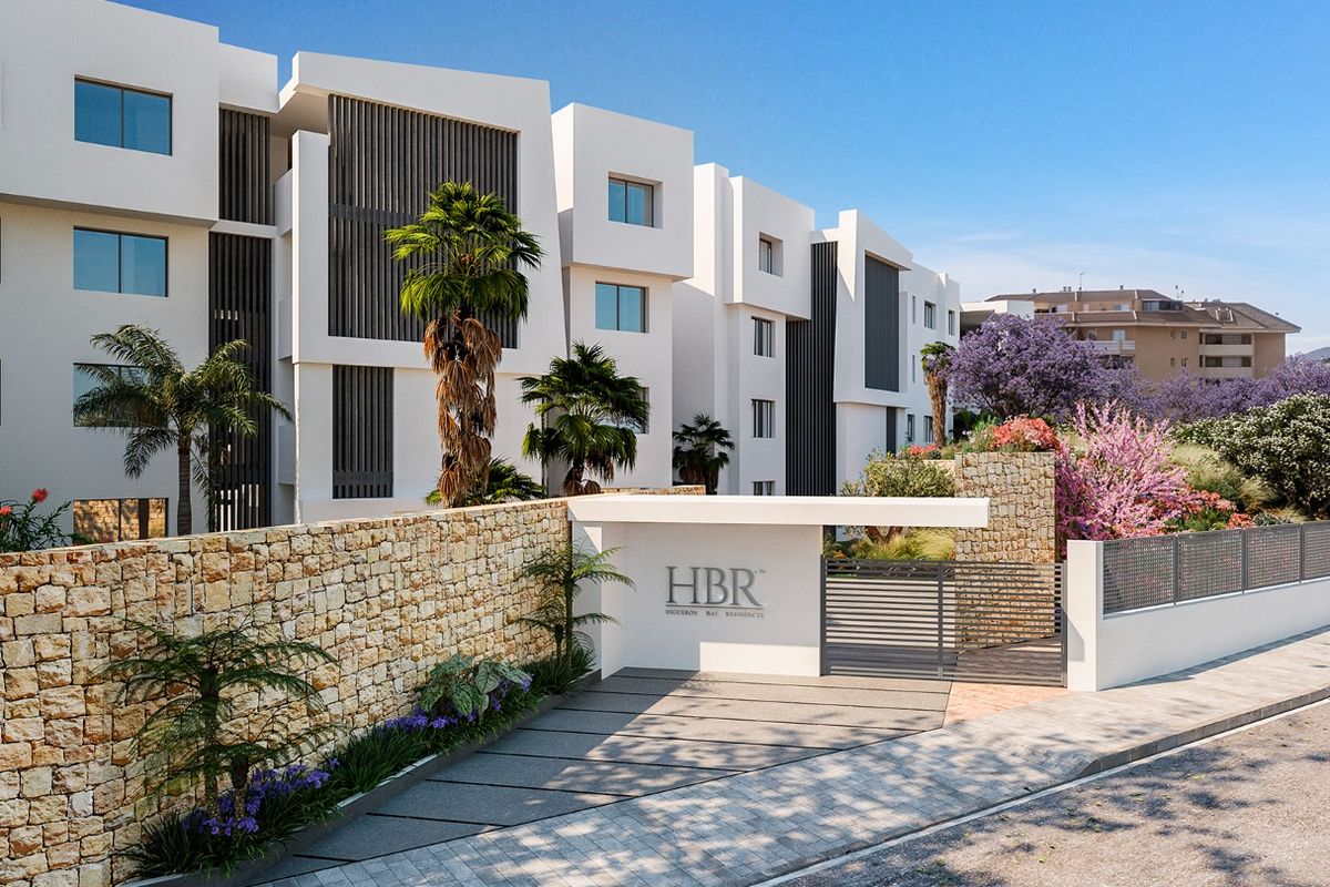 Verwelkomende ingang van een modern appartementencomplex in Fuengirola, omringd door weelderige beplanting.
