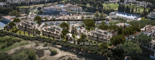 Luchtfoto van een modern 3-slaapkamer penthousecomplex in Marbella, omgeven door weelderig groen en schilderachtige heuvels.
