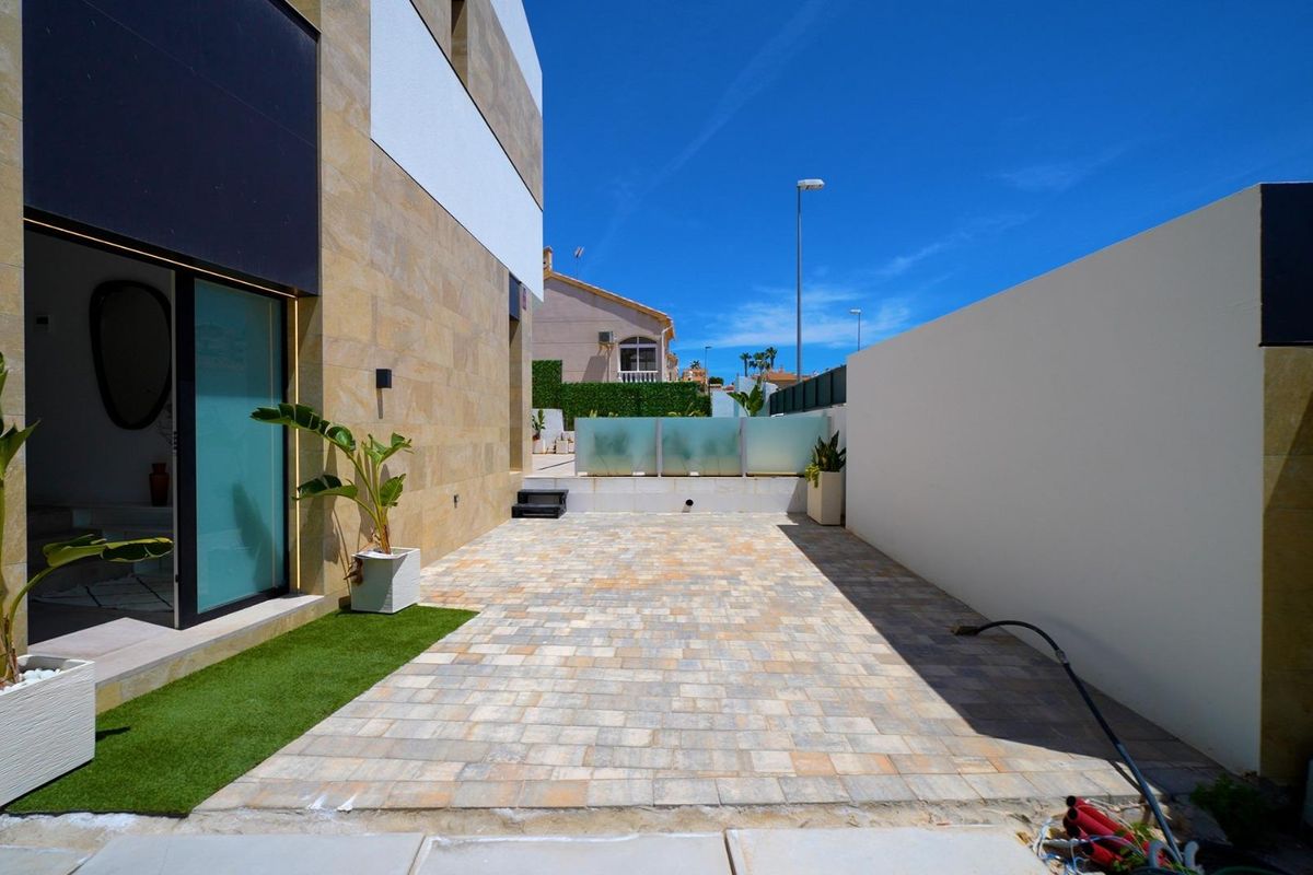 Zijaanzicht van de moderne villa in Orihuela Costa met prachtige steen en landscaping.