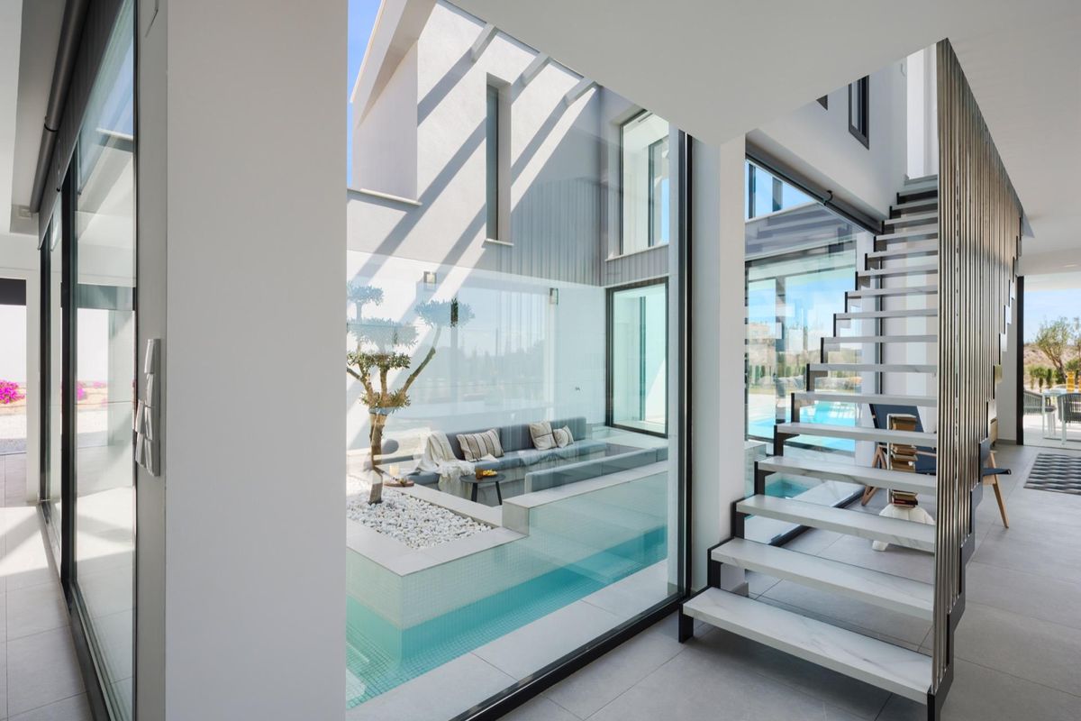 Modern staircase leading to living areas in a 4-bed villa in Baños y Mendigo, featuring glass walls.