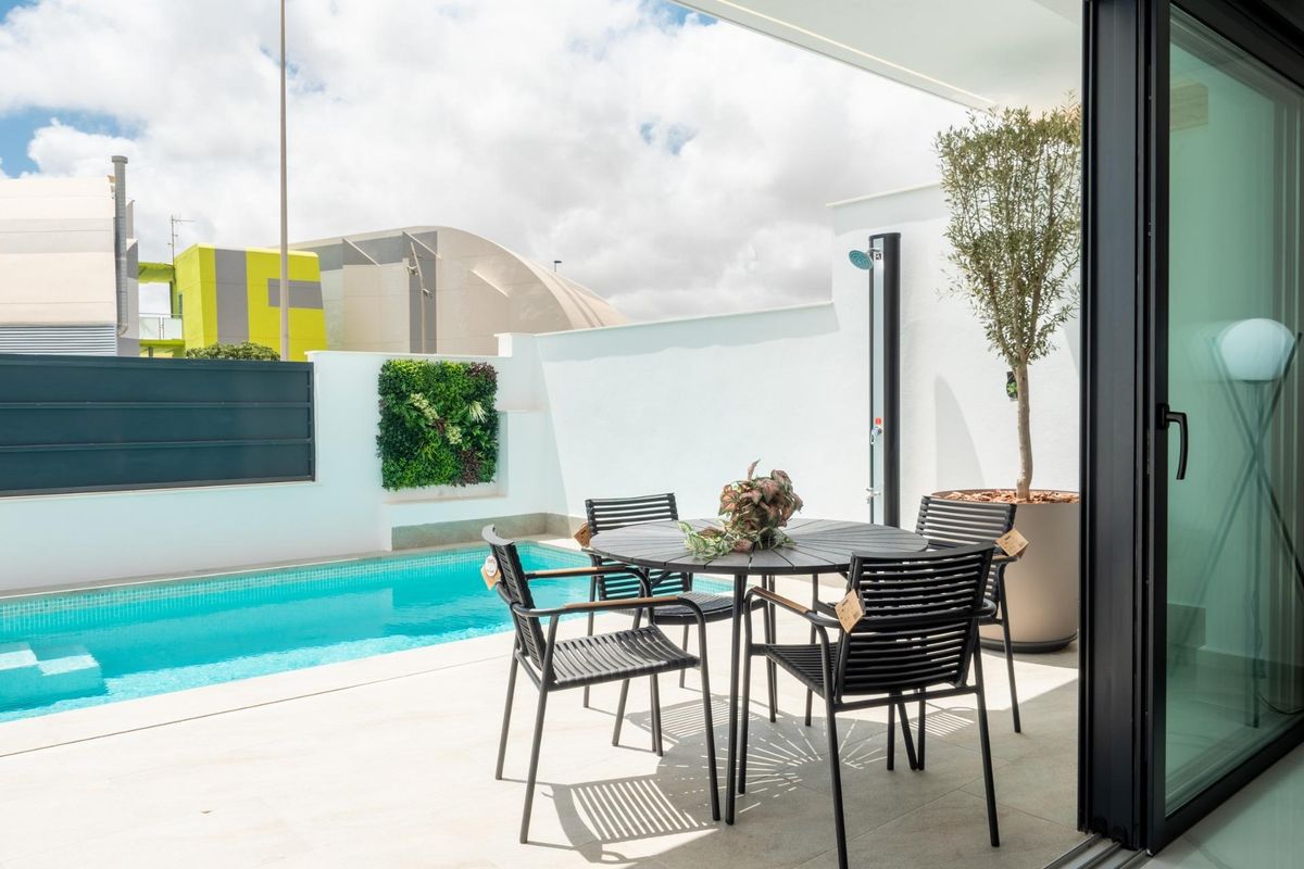Charmant terras met eetset naast het zwembad in de tuin van een moderne villa in San Pedro del Pinatar.