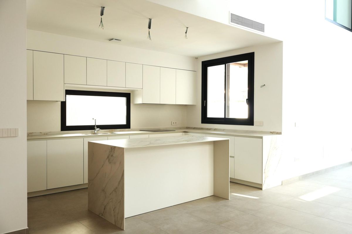 Een andere hoek van de moderne keuken in de villa in Alfas del Pi, met een stijlvolle kookeiland en kasten.