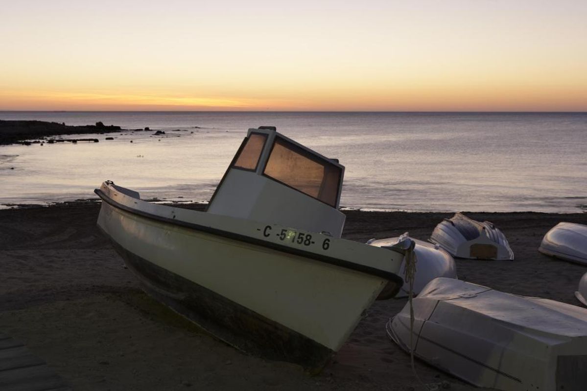 Kleurige zonsondergang boven een strand met kleine boten, vastgelegd op een rustige avond nabij Torrevieja.