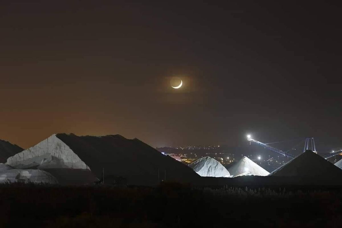 Nachtbeeld van zoutbergen in Torrevieja, verlicht door een maansikkel onder de sterrenhemel.