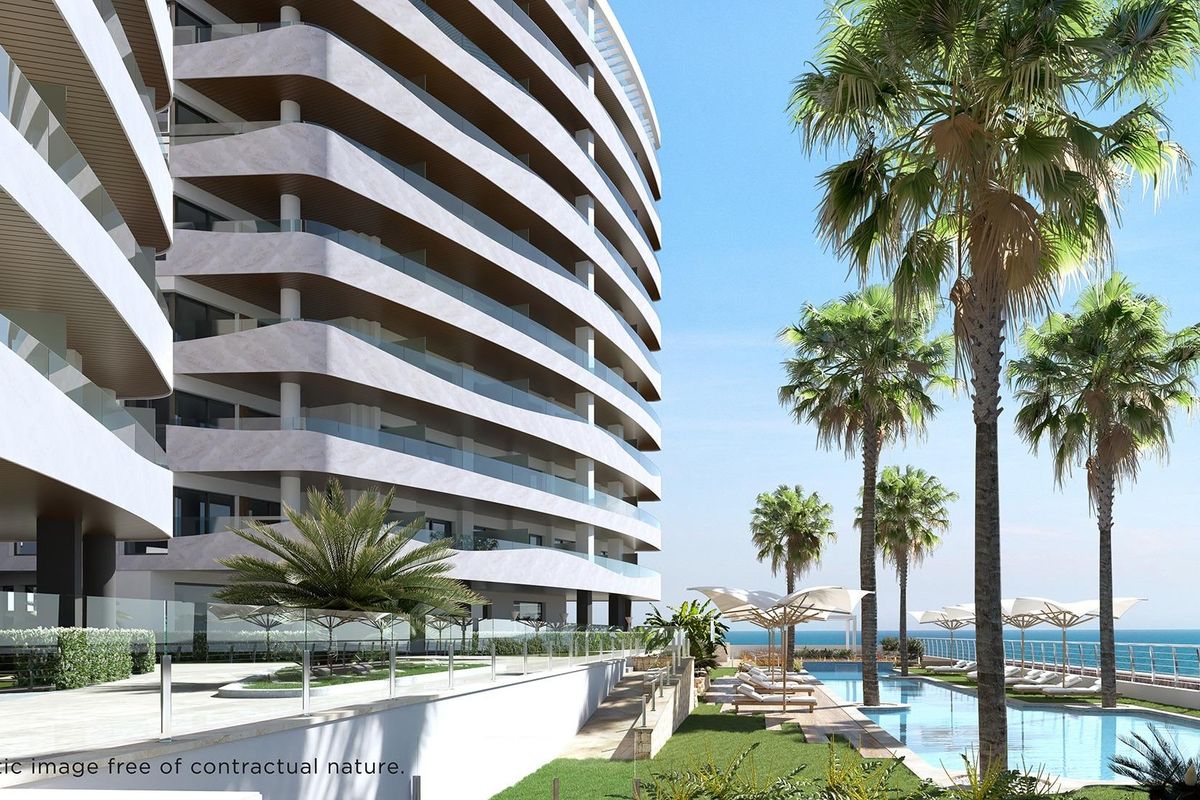 Exterior view of modern apartment building with palm trees, pool, and sea in La Manga del Mar Menor.