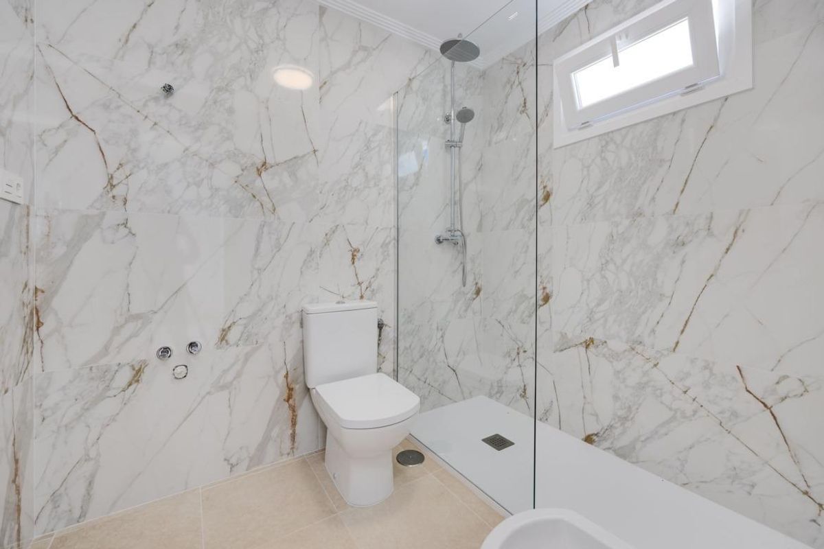 Moderne badkamer in een 3-slaapkamer villa in San Fulgencio, met elegante marmeren muren en een ruime douche.