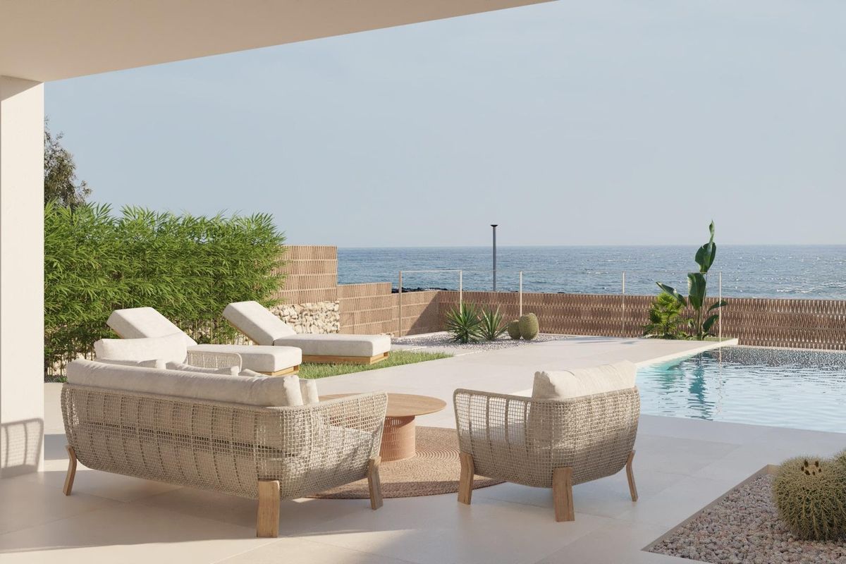 Stijlvol terras met zitplaatsen met uitzicht op het zwembad en de oceaan, onderdeel van een herenhuis aan de kust van Spanje.