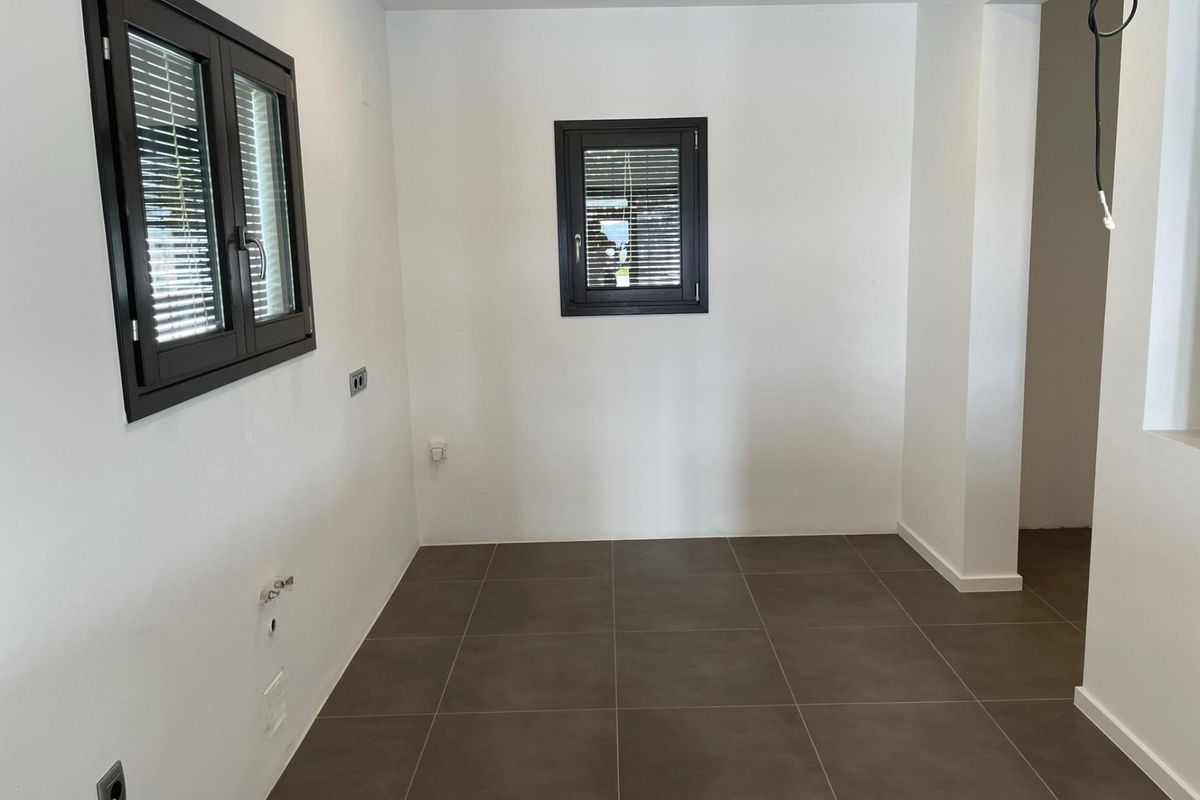 Ruimtelijke ruimte met lichte muren en donkere tegels, biedt flexibiliteit in een villa in Moraira Teulada.