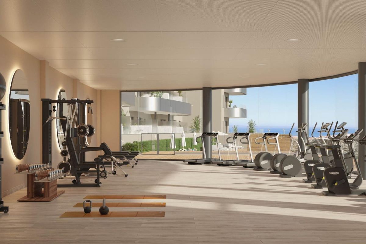 Moderne sportschool vol met apparatuur en natuurlijk licht in een appartementencomplex in Torremolinos.