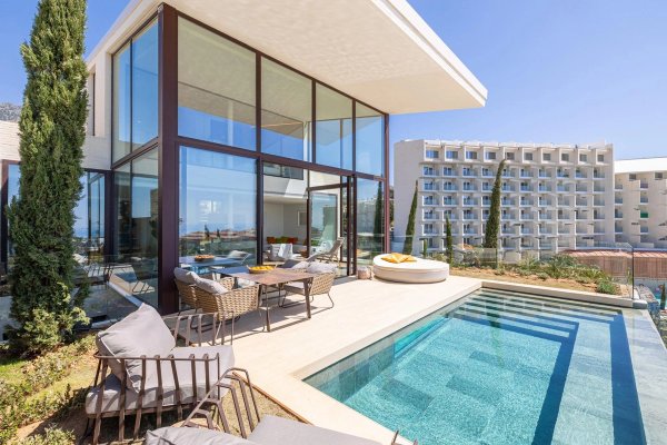 Moderne 4-slaapkamer herenhuis in fuengirola met een zwembad en zithoek buiten naast een glazen woonruimte.