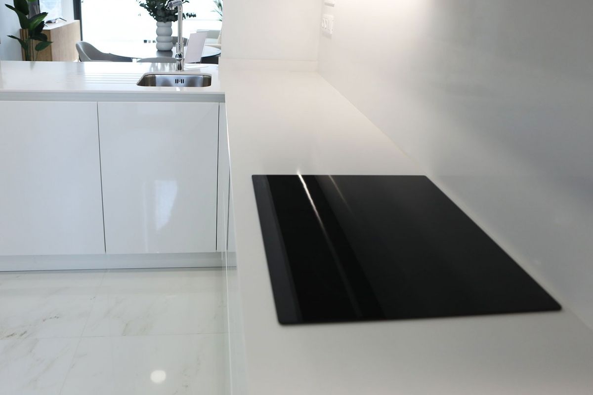 Moderne keuken met strakke zwarte kookplaat en witte kasten in een appartement in Benidorm. 3-slaapkamerindeling.
