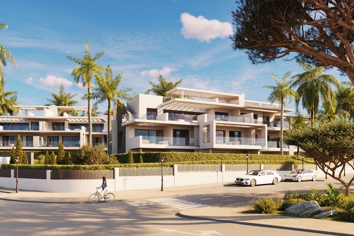 Heldere dagzicht op moderne penthouses met palmbomen langs de straat in Estepona, Costa del Sol.