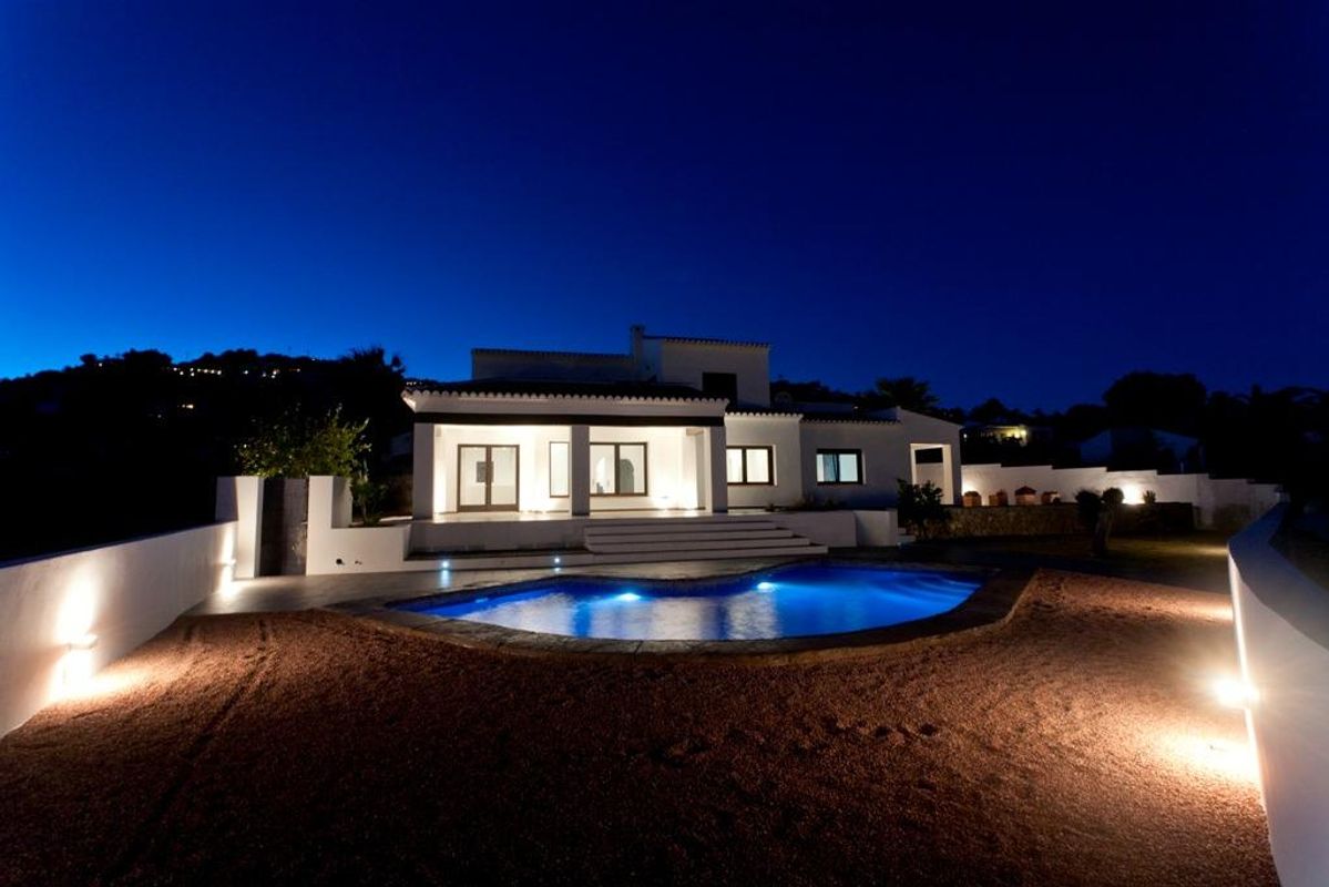Nachtzicht van de villa met buitenverlichting en zwembadgebied in Moraira Teulada, Costa Blanca Noord.