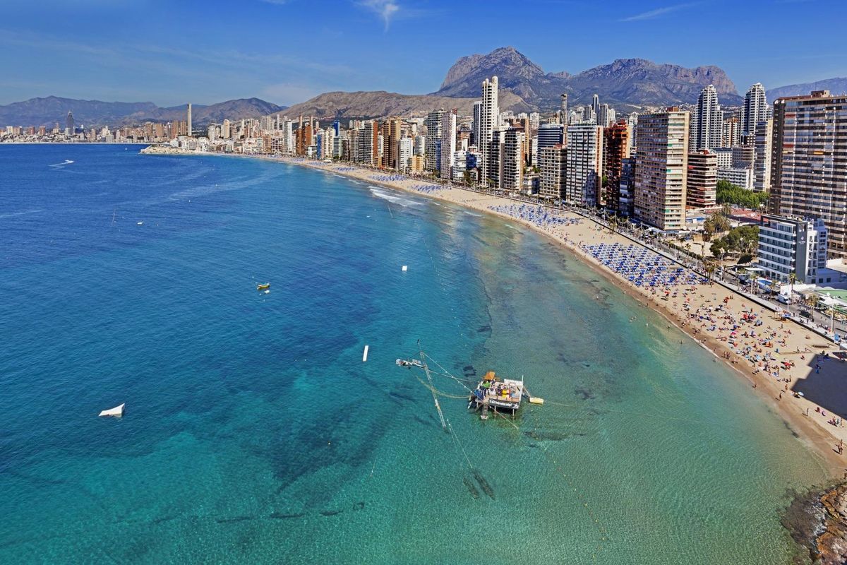 Levendig uitzicht op de kustlijn van Benidorm met hoge gebouwen langs het zandstrand.