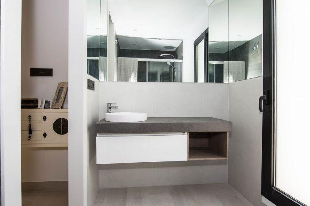 Minimalistische badkamer met witte muren en grijze wastafel in moderne Spaanse villa