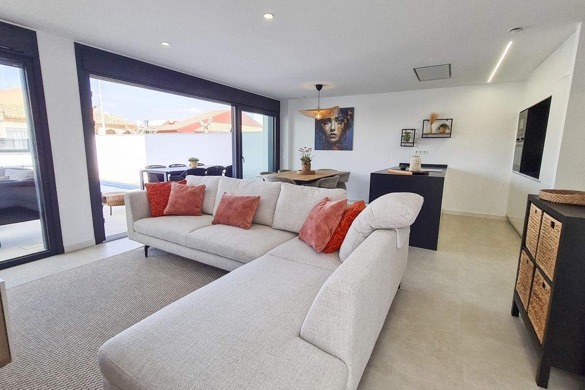 Heldere woonkamer met een hoekbank en terras toegang in een rijtjeshuis, San Pedro del Pinatar, Spanje.