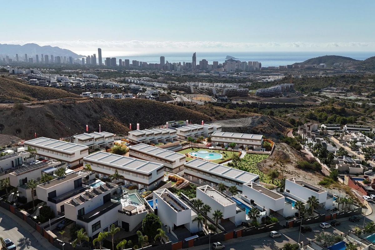 Luchtfoto van woningen met de kustlijn en stadssilhouet van Benidorm op de achtergrond, Finestrat.