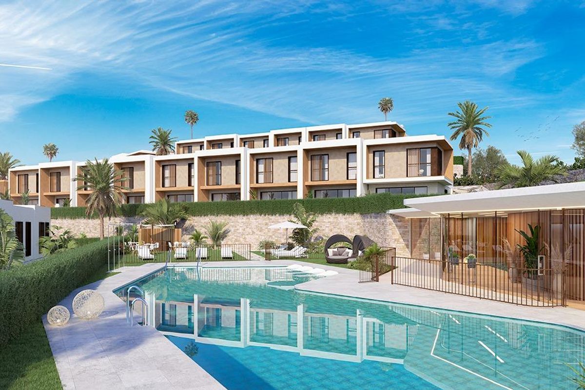 Buitenaanzicht van huizen met een zwembad in Mijas, Costa del Sol, met weelderig groen en blauwe luchten.