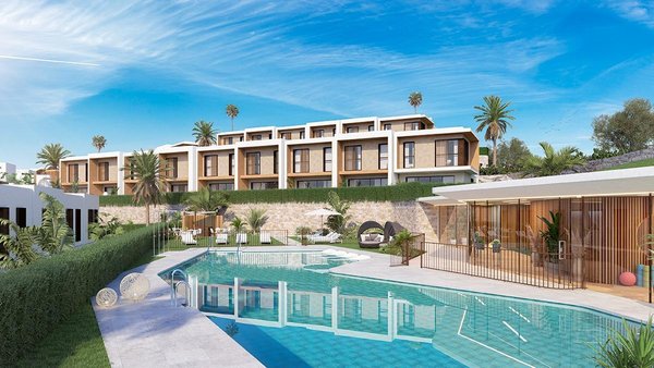 Buitenaanzicht van huizen met een zwembad in Mijas, Costa del Sol, met weelderig groen en blauwe luchten.