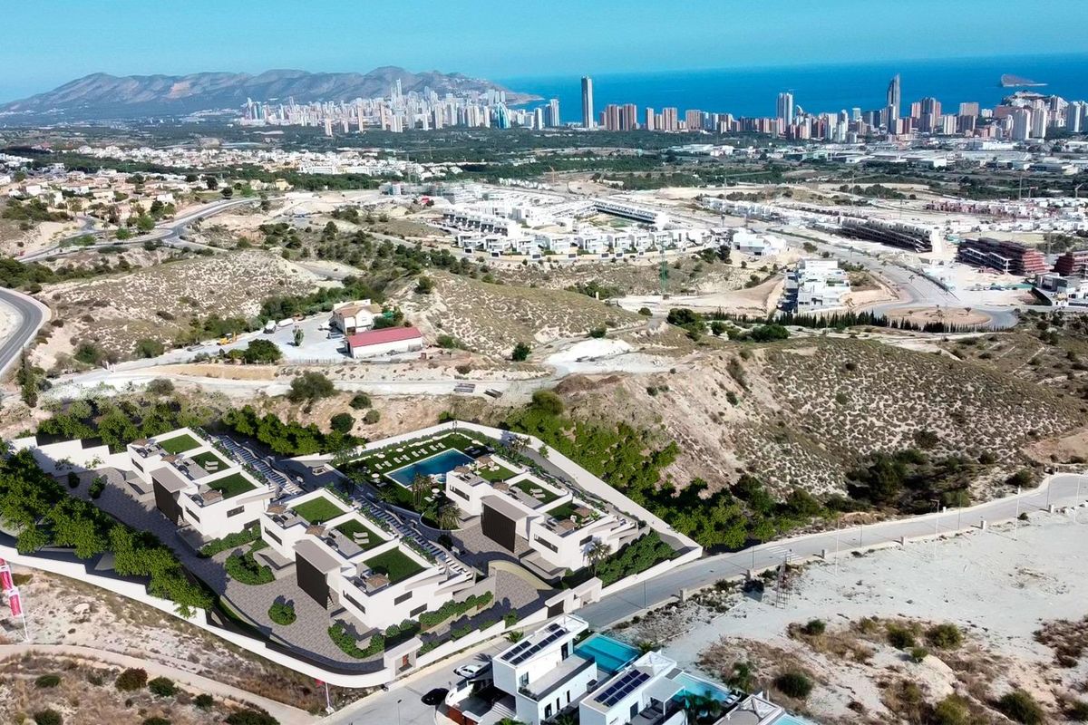 Luchtfoto van een 3-slaapkamer bungalowontwikkeling in Finestrat, met uitzicht op de heuvels en skyline.