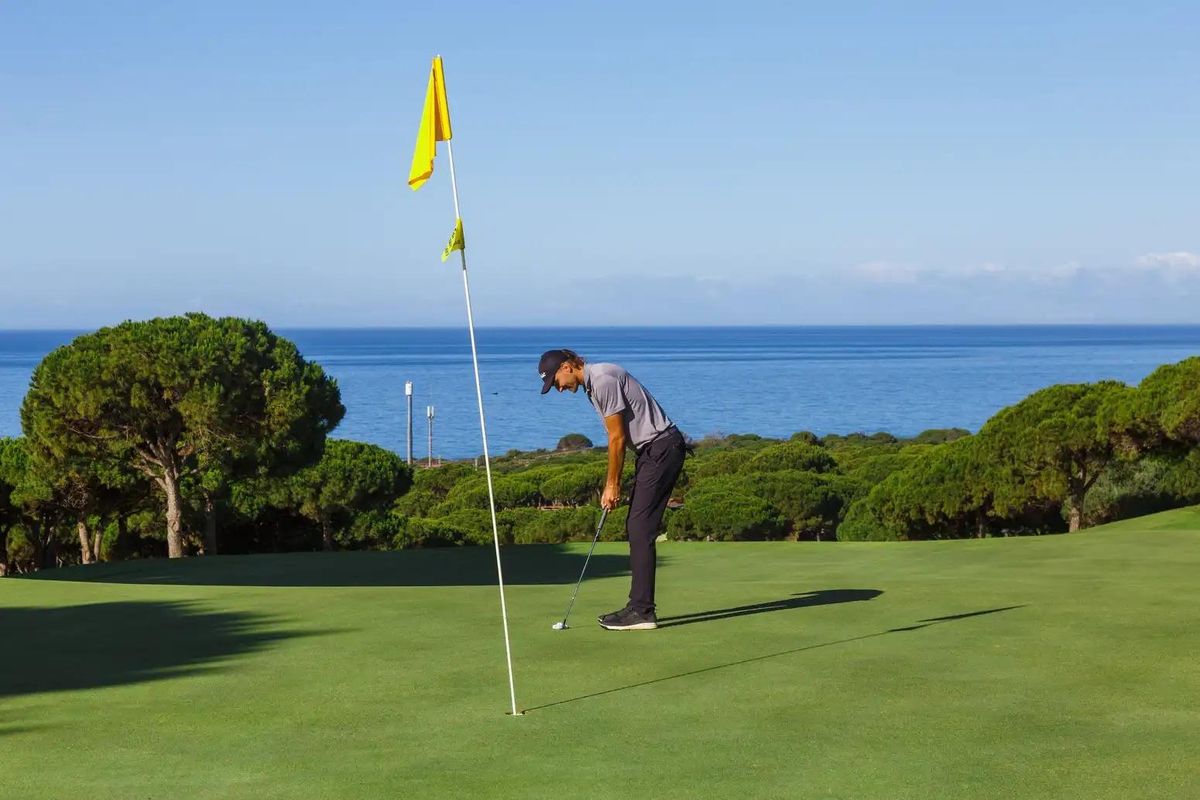 Golfspeler die zich voorbereidt om te putten op een baan met een prachtig uitzicht op de kust in Marbella.