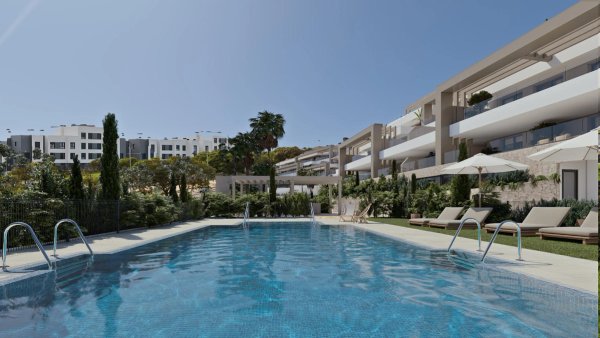 Een zwembad met ligstoelen en palmbomen bij een nieuw appartementencomplex in Estepona, Costa del Sol.