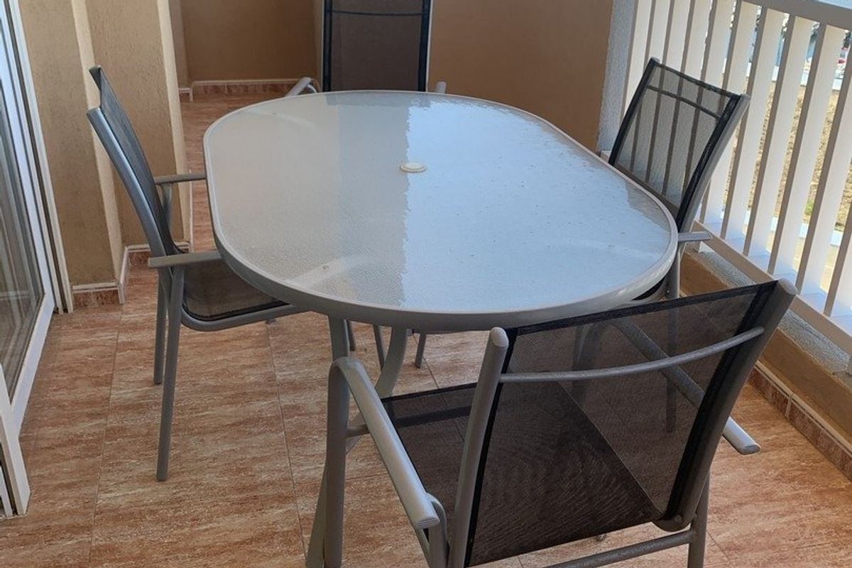 Eettafel en -stoelen op het terras, met uitzicht op de boten van de jachthaven in La Manga del Mar Menor.