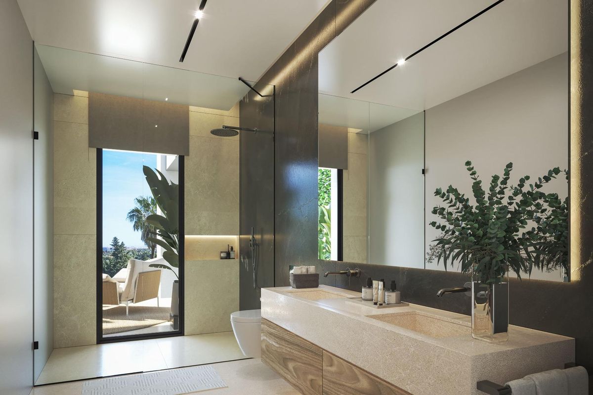 Ruime badkamer in een villa in estepona met dubbele wastafel, grote spiegel en inloopdouche. natuurlijk licht van een groot raam.