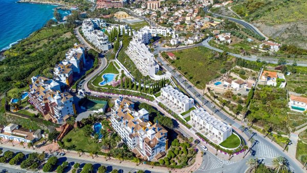 Luchtfoto van een modern appartementencomplex in Almuñecar, met zwembaden en aangelegde tuinen.