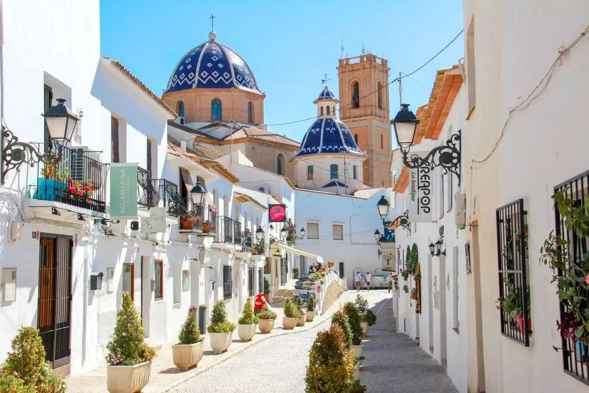Schitterende straat in Altea, omzoomd met winkels en cafés, toont de mooie architectuur en levendige sfeer.