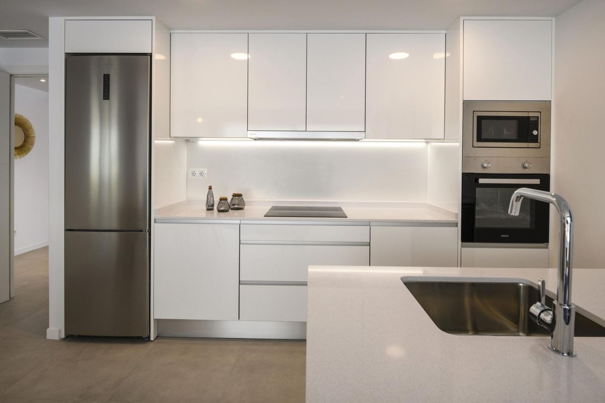 Moderne keuken in Orihuela Costa, uitgerust met strakke kasten en apparaten.