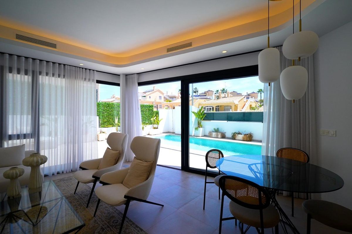 Uitzicht vanuit de eetruimte naar het zwembad, benadrukt de buitenruimte van een 3-slaapkamer villa in Orihuela Costa, Spanje.