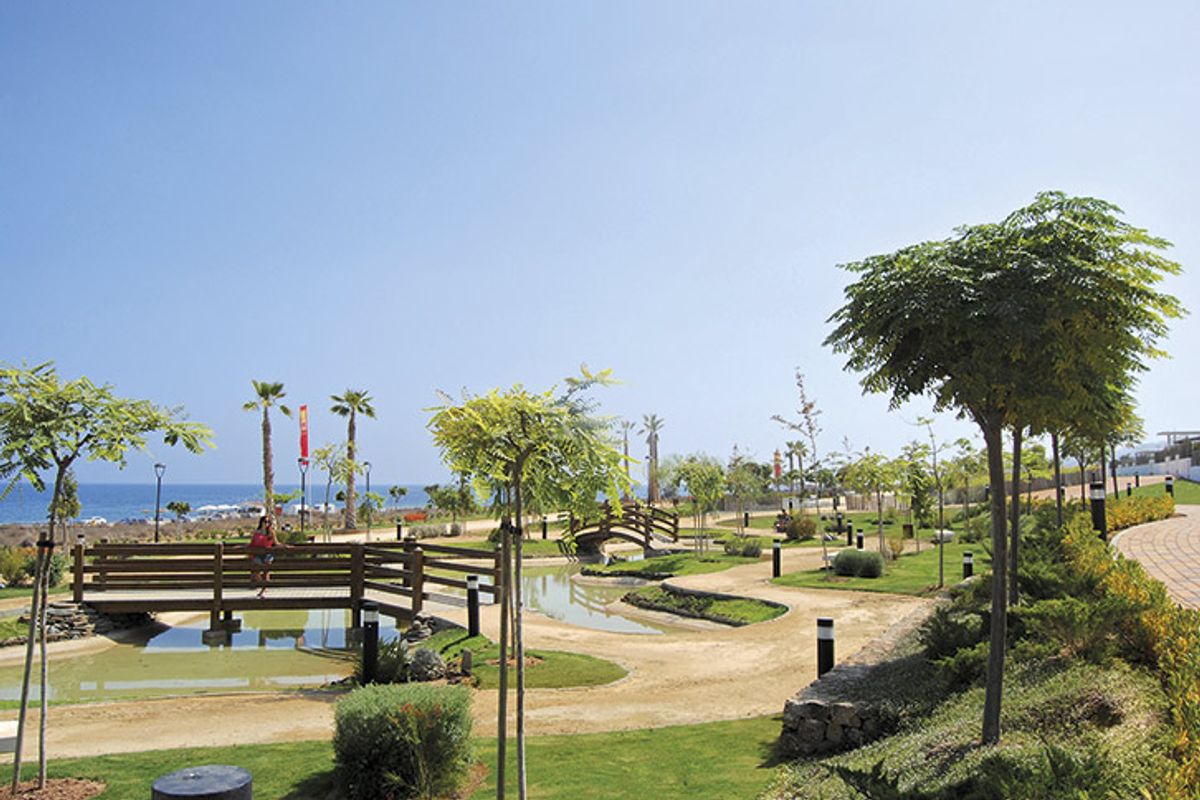 Aangelegde kustelijke tuin met houten brug, palmbomen en wandelpaden nabij de zee in Mar de Pulpi