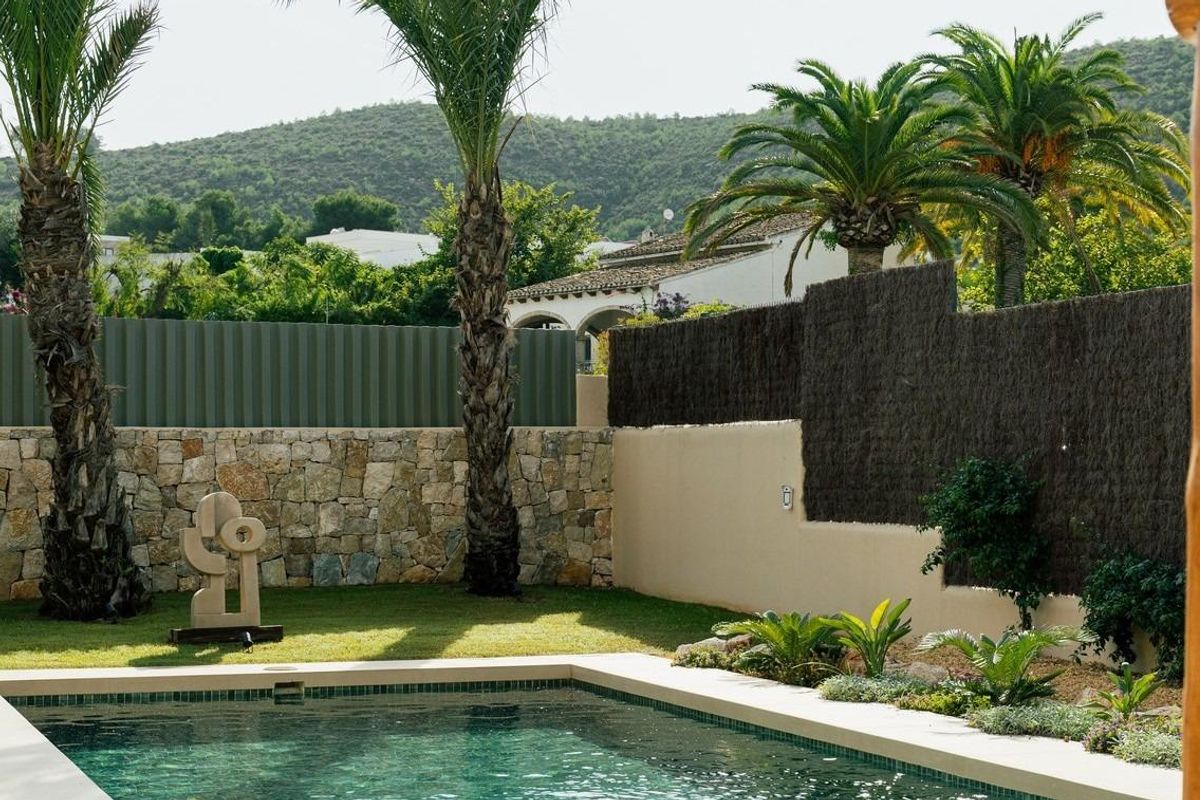 Dichtbijzicht op het zwembad omrand door palmbomen en stenen muren in de villa in Jávea.