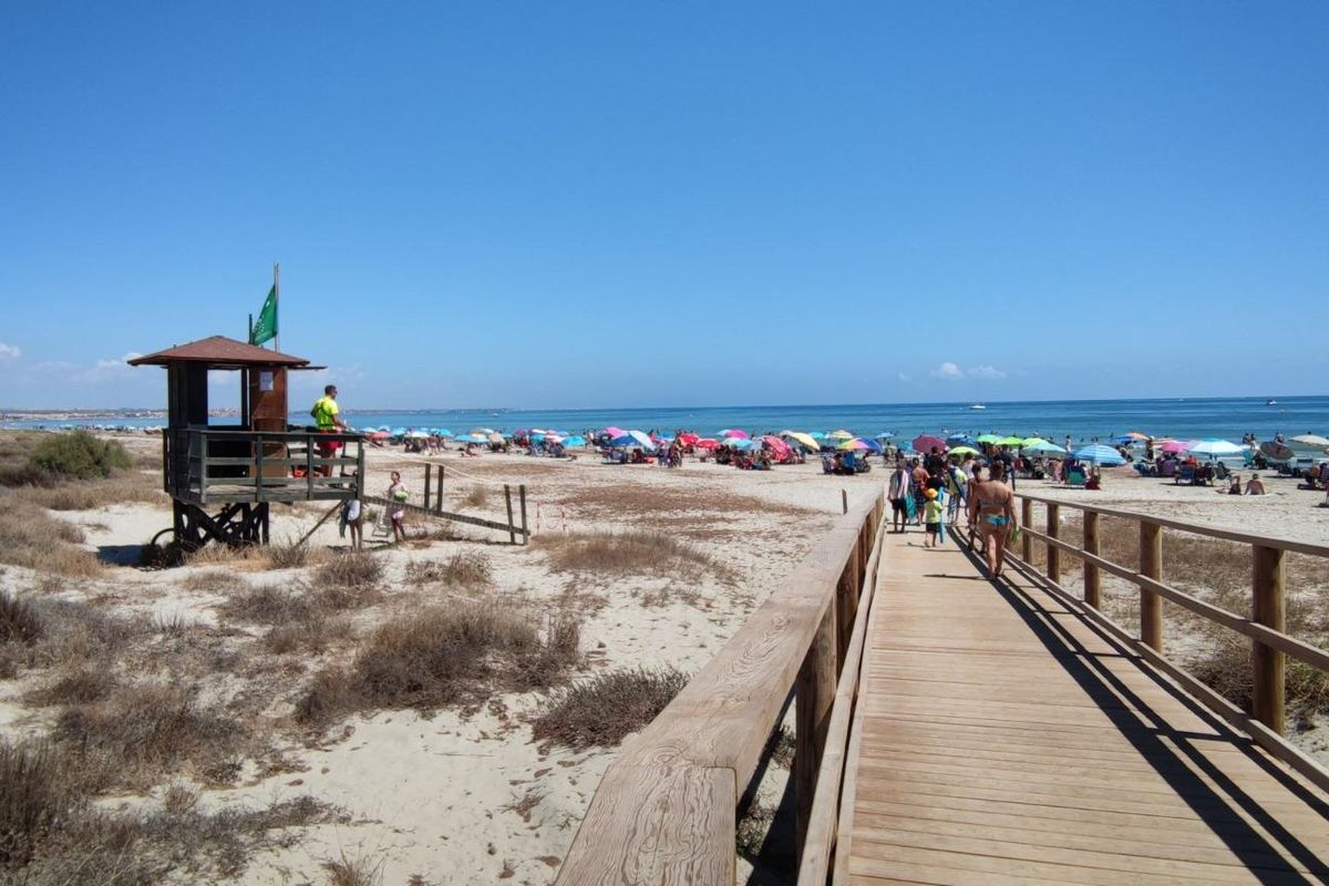 Zonovergoten strand nabij San Pedro del Pinatar, vol met parasols en zonnebaders, perfect voor recreatie.