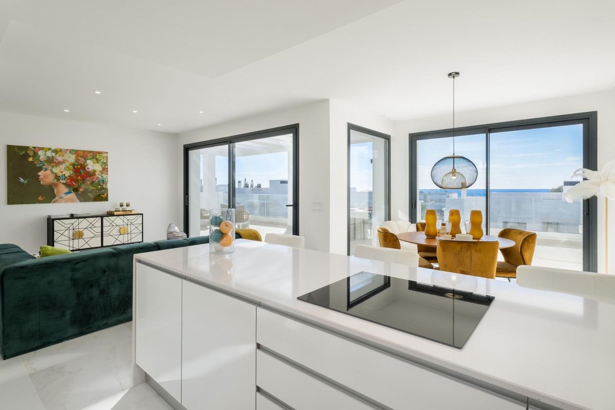 Stijlvolle woonkamer en eetruimte in penthouse in Estepona, met grote glazen deuren en uitzicht op zee.