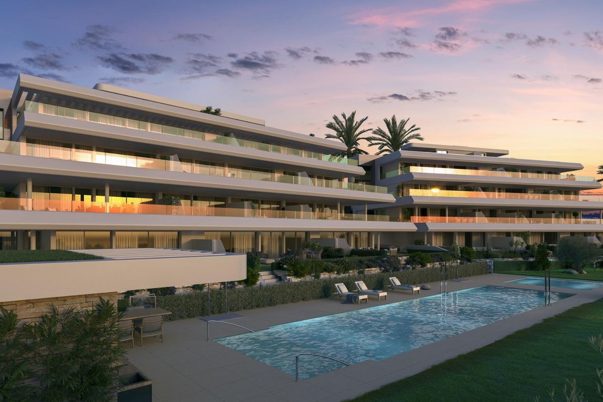 Zicht op het appartementencomplex in Estepona met zonsondergang die op de ramen reflecteert.