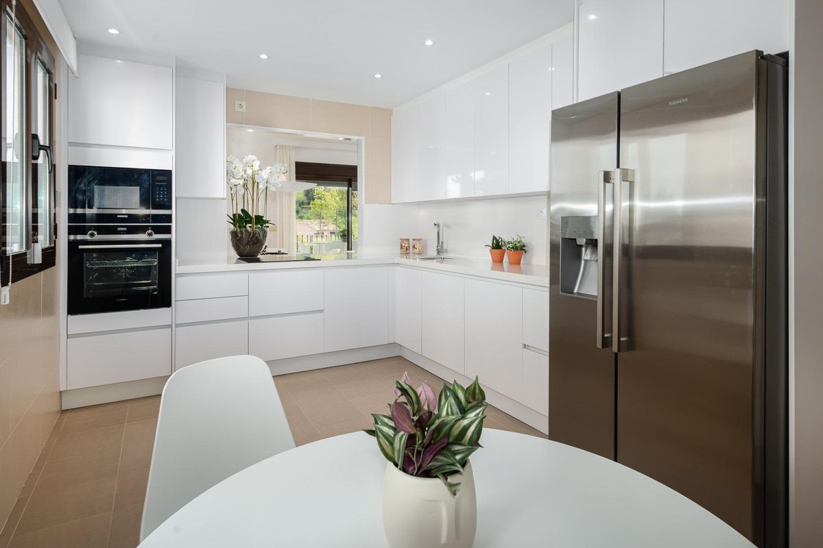 Stijlvolle keuken met witte kasten en een eetplek in de villa in Estepona, ontworpen voor gemak.